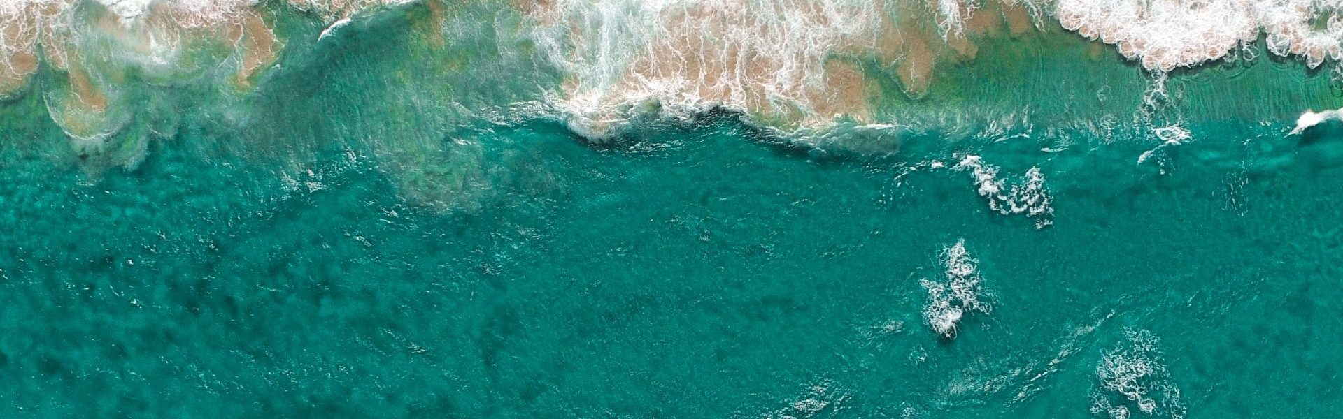 Aerial photo of waves breaking on a shore.